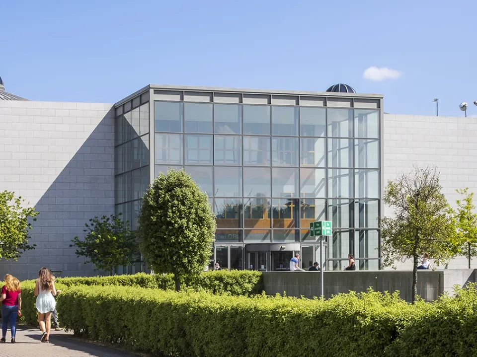 The glass-fronted main entrance of the John & Aileen O'Reilly Library on a sunny day.